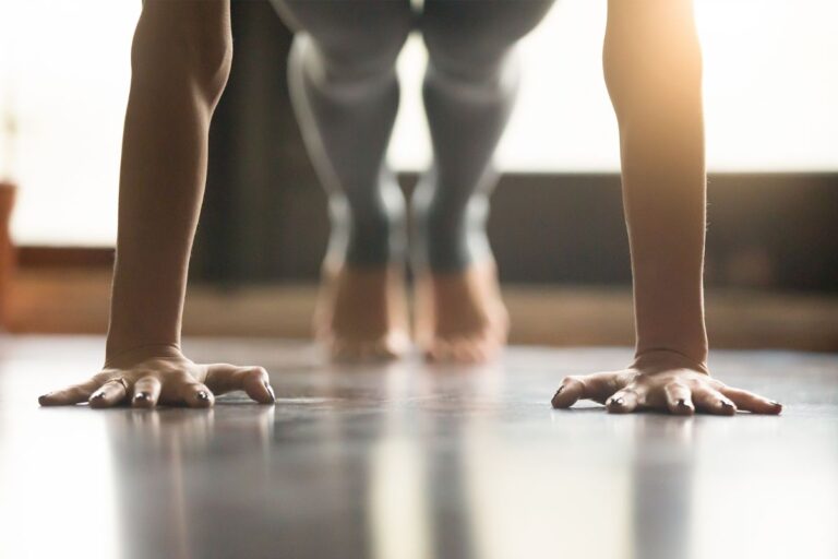 Young woman does pushups in sunlit room.