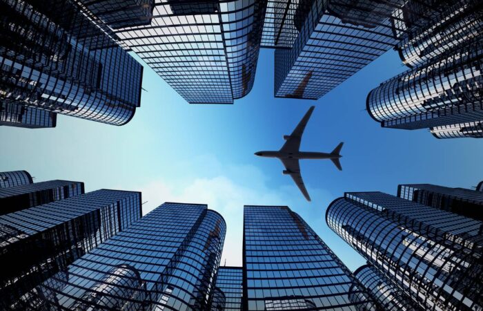 Photo looking up through a line of skyscrapers to view an airplane flying overhead