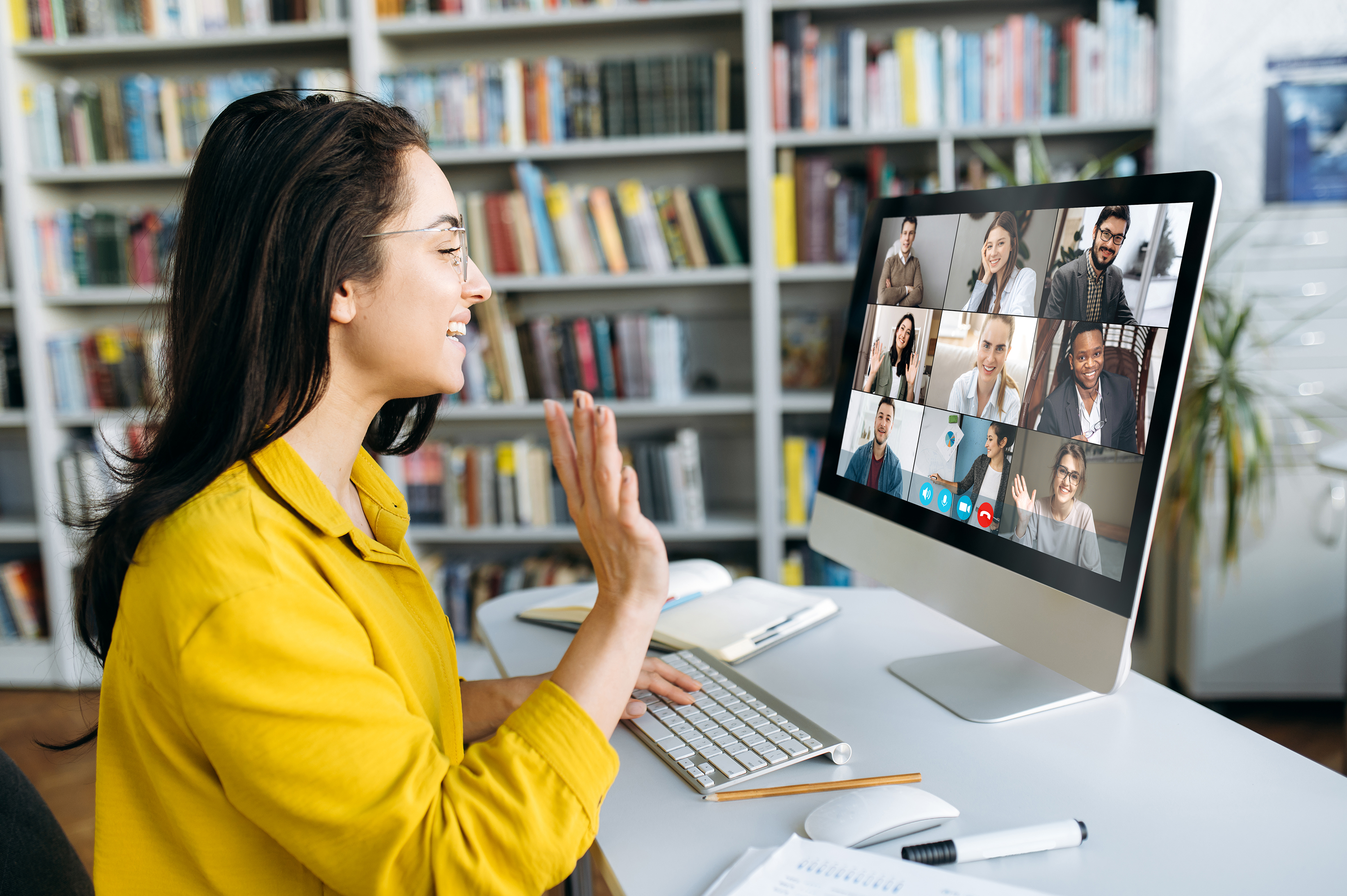 Photo of a young woman sitting at a computer at home on a virtual meeting with coworkers