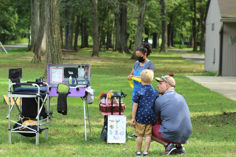 Synergist and son getting balloon animals made by balloon artist at company picnic