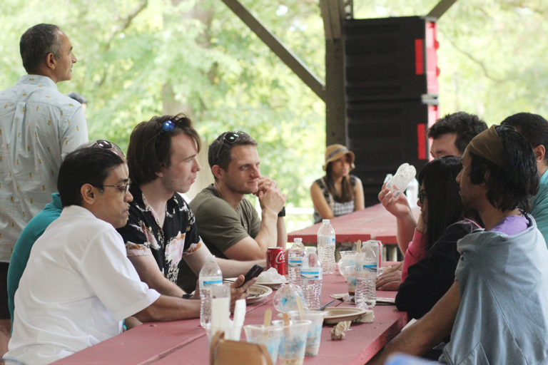 Photo of team of Synergists sitting and talking with one another at the company picnic