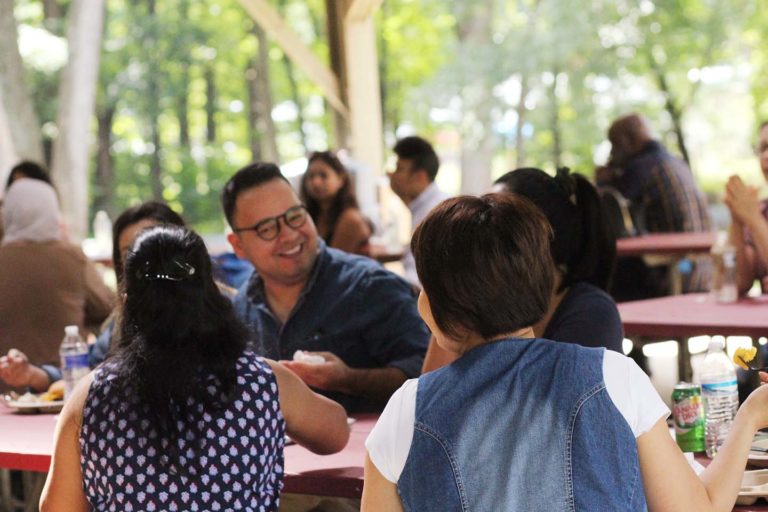 Photo of Synergists at the company picnic talking to one another