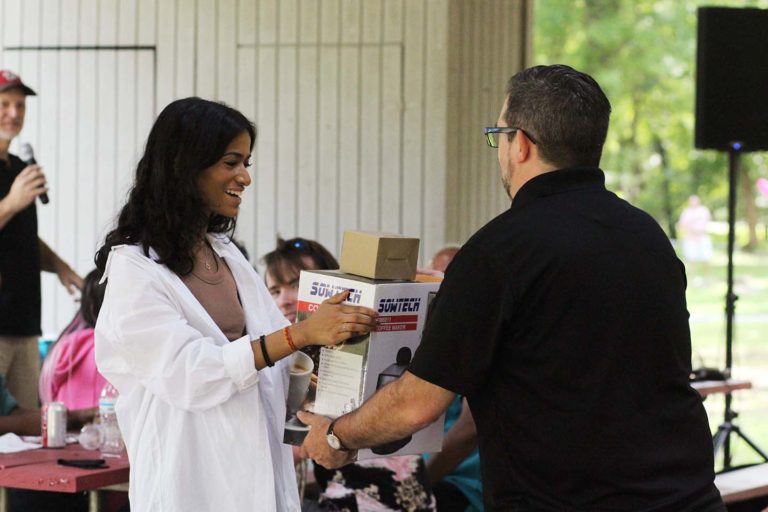 Photo of young woman giving Synergist a raffle prize