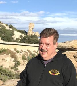 Rod standing in front of a large stone structure.