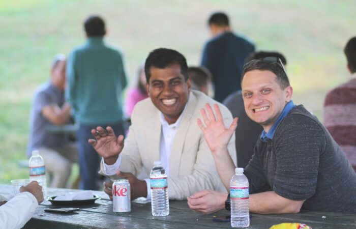 Synergists Ravi Rudra and Daniel Streicher wave and smile for a photo.