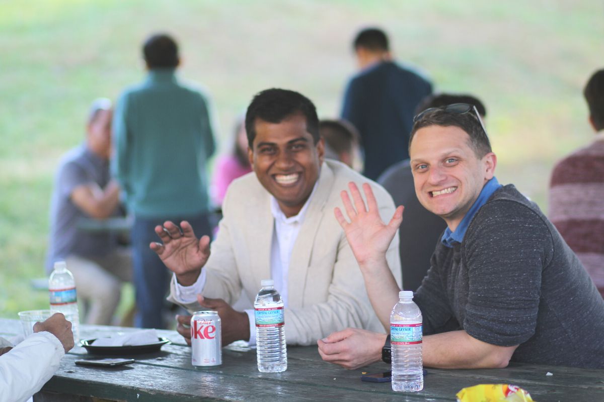 Synergists Ravi Rudra and Daniel Streicher wave and smile for a photo.